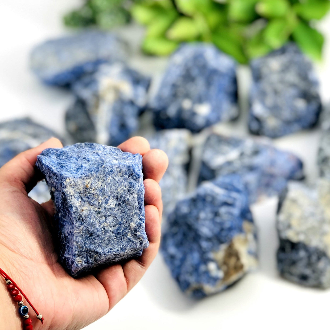 one sodalite rough stone piece in hand for size reference with many others in the background