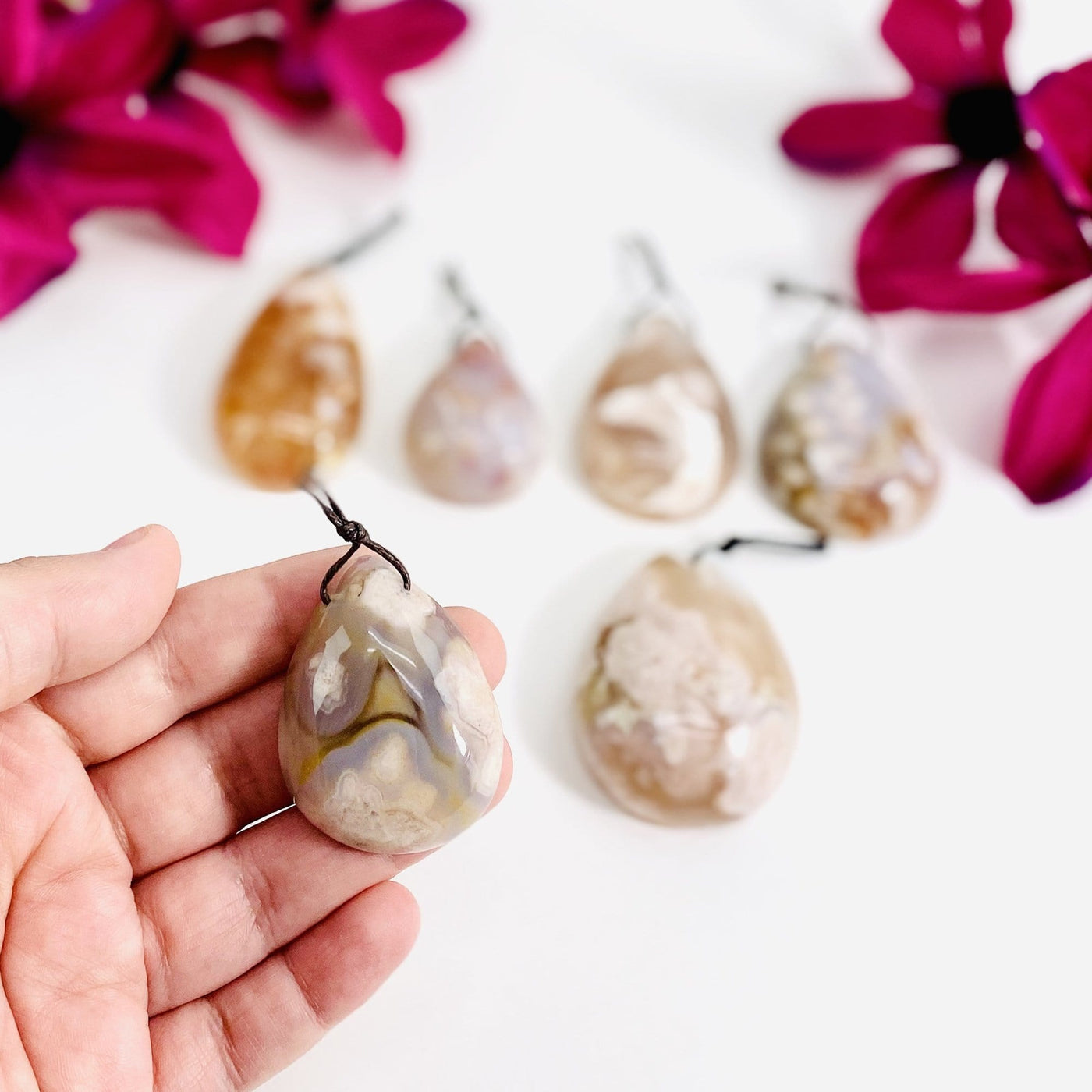 Flower Agate Tumbled Pendants gripped in fingers