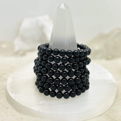 7 black Agate bead bracelets stacked on top of each other on stand