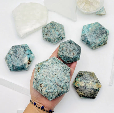 two different sizes of amazonite hexagons being held, for size reference.