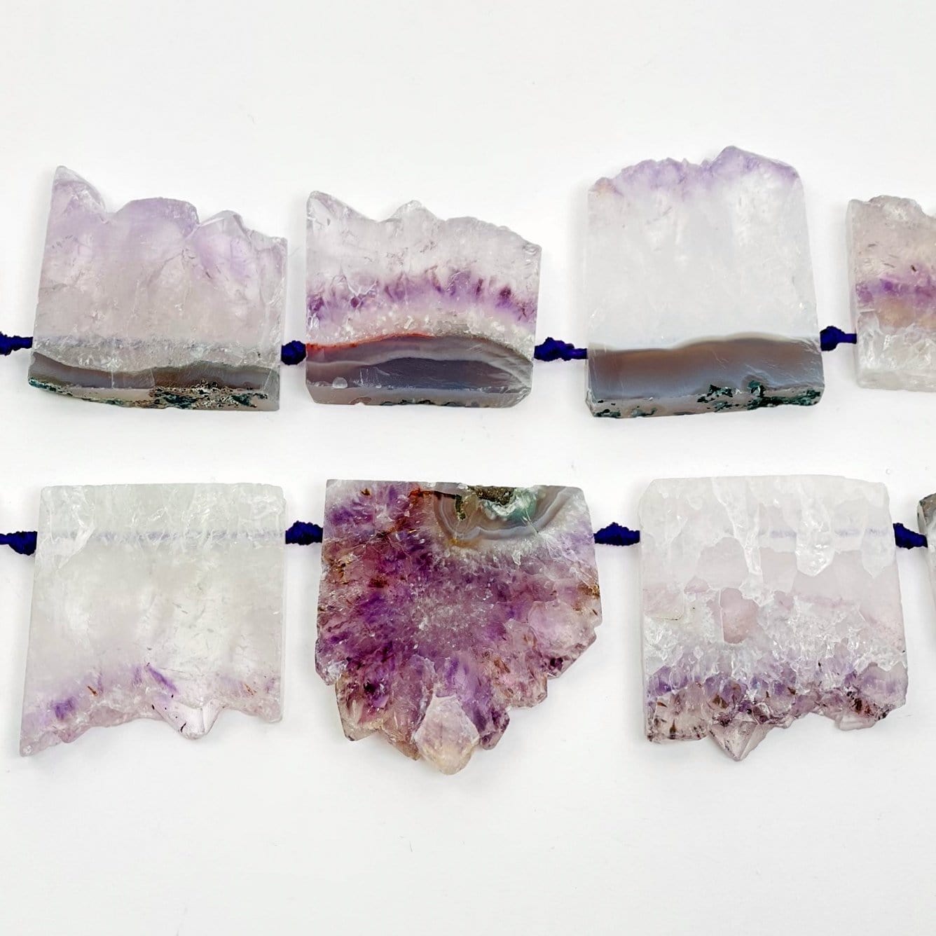 Up close shot of string of amethyst slice beads on white background