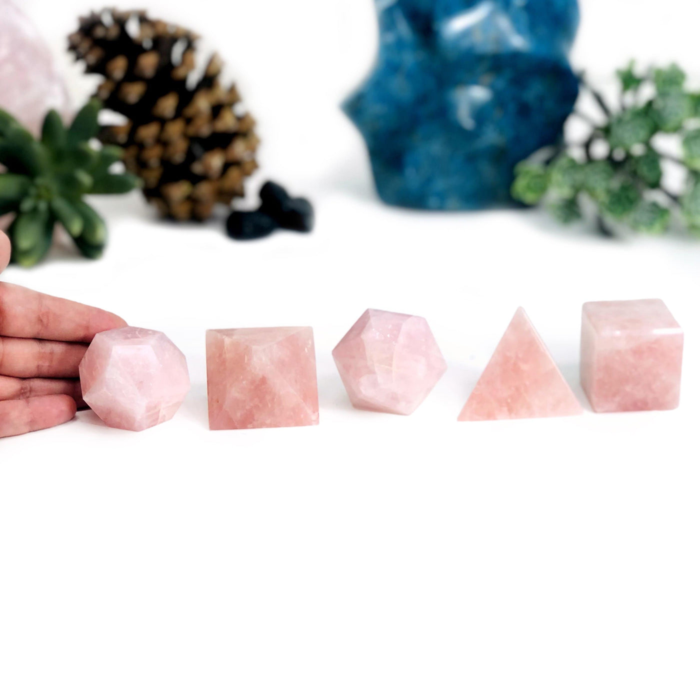 Hand touchhing Rose Quartz Sacred Geometry Meditation Set with decorations blurred in the background