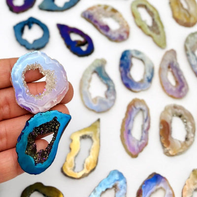 picture of two of our agate slices titanium coated being held for size reference.