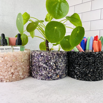 3 Tumbled Stone Pot/Holders #4 up close, a rose quartz holder holding oil bottles, the amethyst one holding a plant and the tourmaline one holding pens