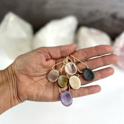 Worry Stone Necklaces in a hand, amethyst, crystal quartz, rose quartz, tigers eye, ruby fuchsite, peach moonstone