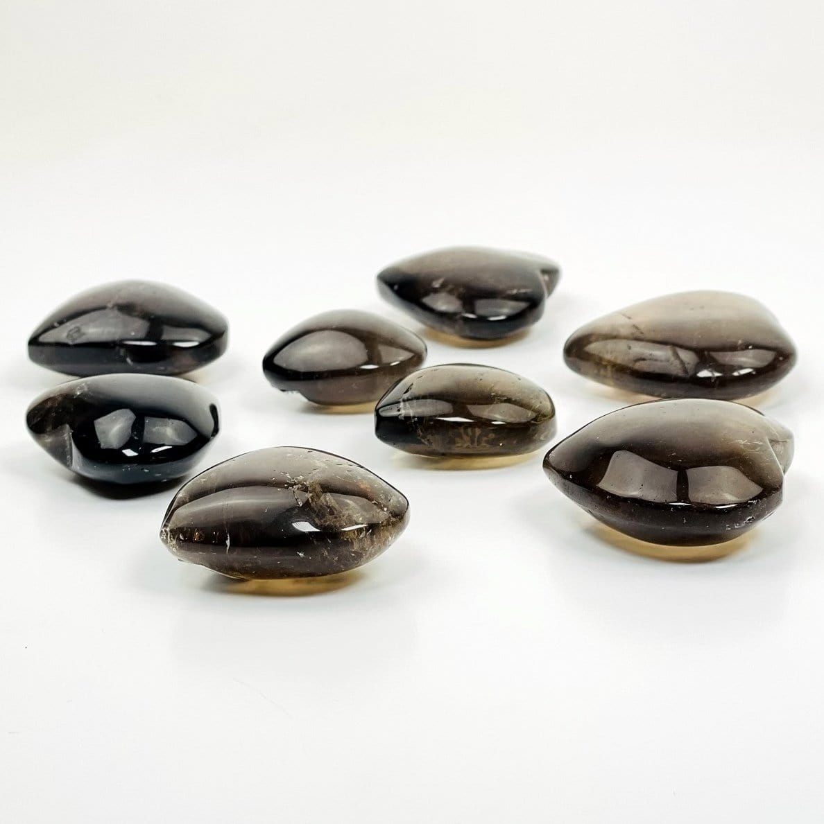 side view of many smokey quartz polished hearts on white background for thickness