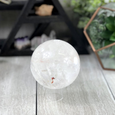 crystal quartz polished sphere with decorations in the background