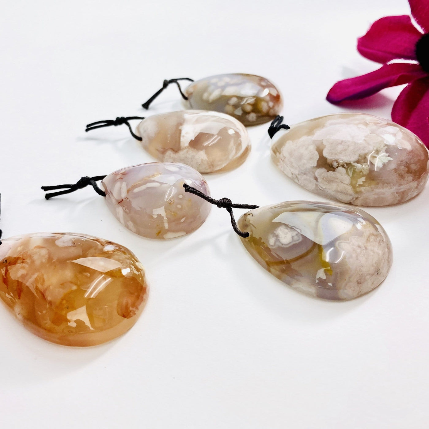 Side view of Flower Agate Tumbled Pendants showing the thickness on white background.