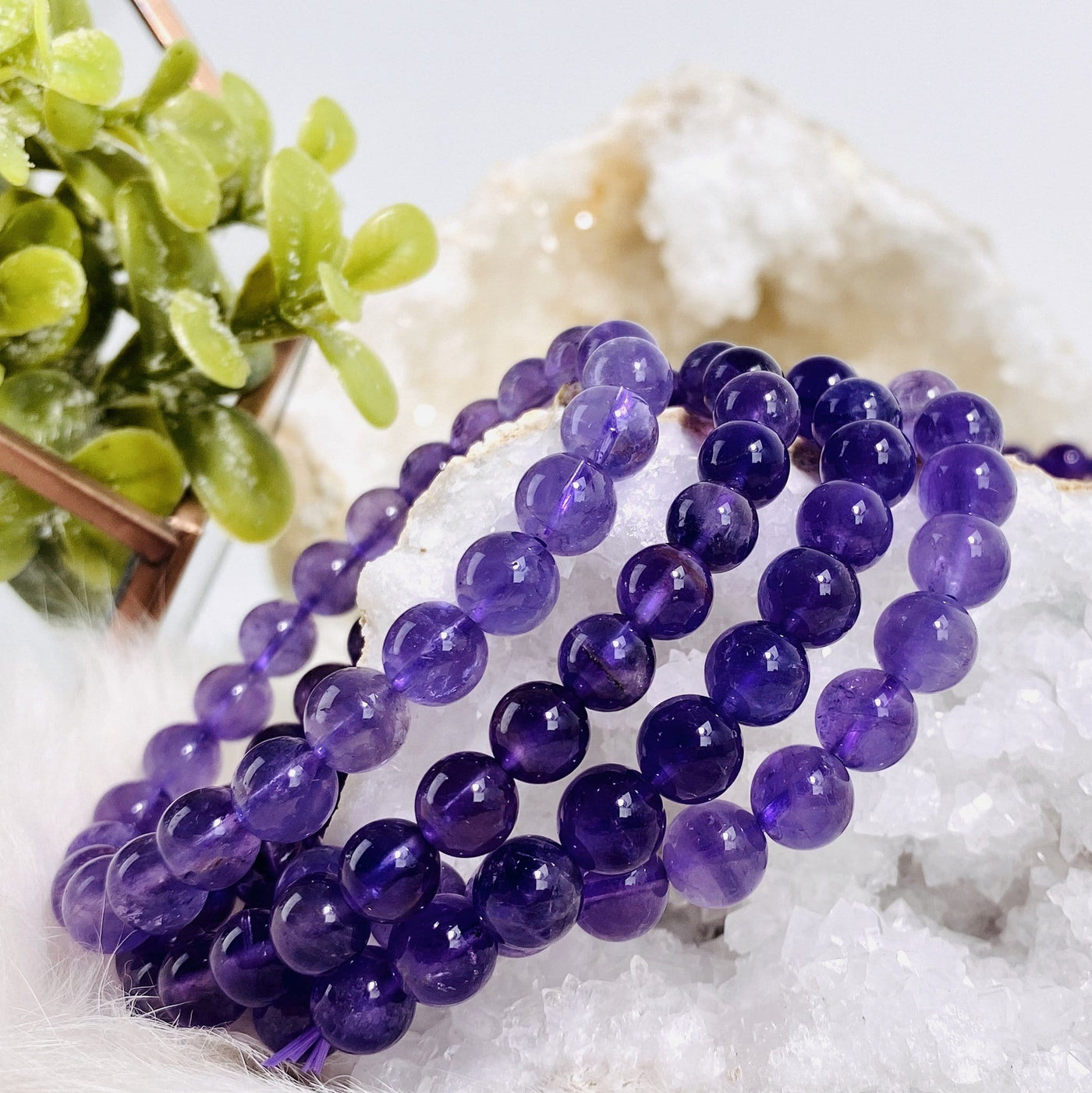 4 amethyst gemstone beaded bracelets displaced on a quartz geode.