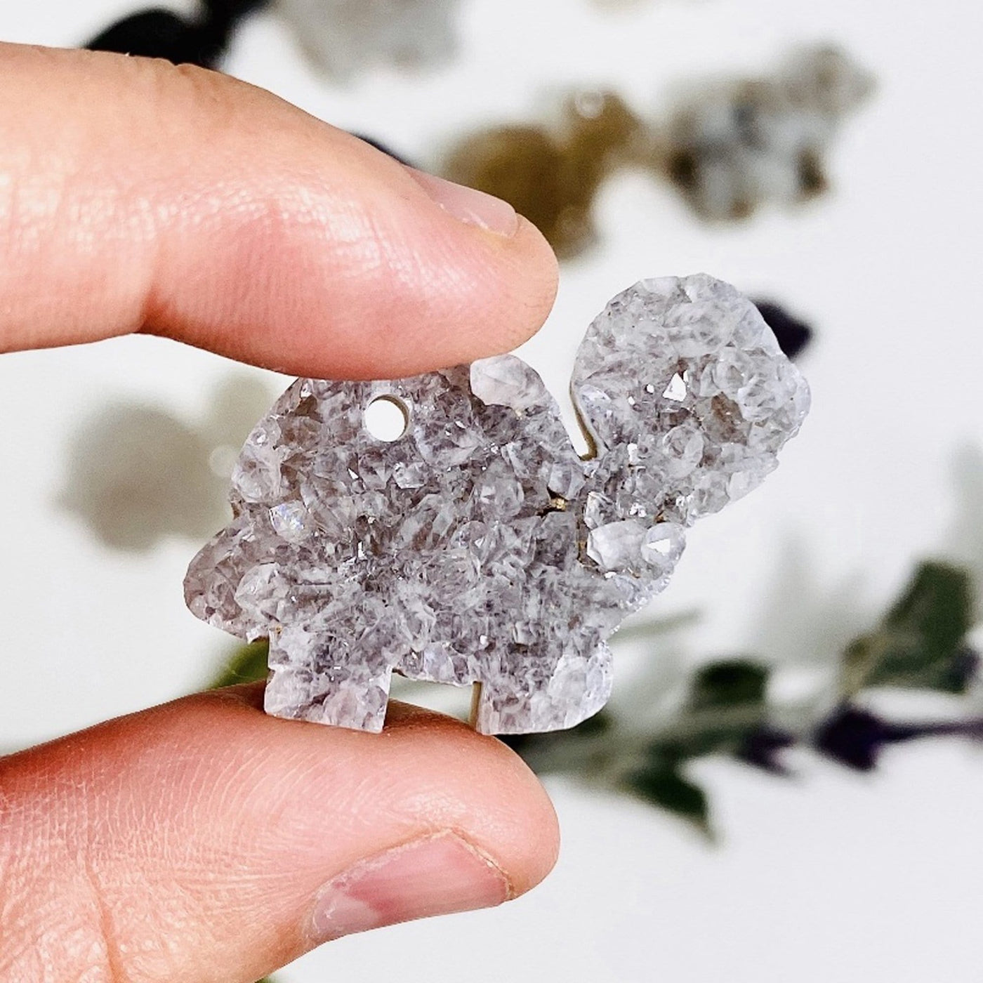 hand holding up druzy turtle cabochon with decorations blurred in the background