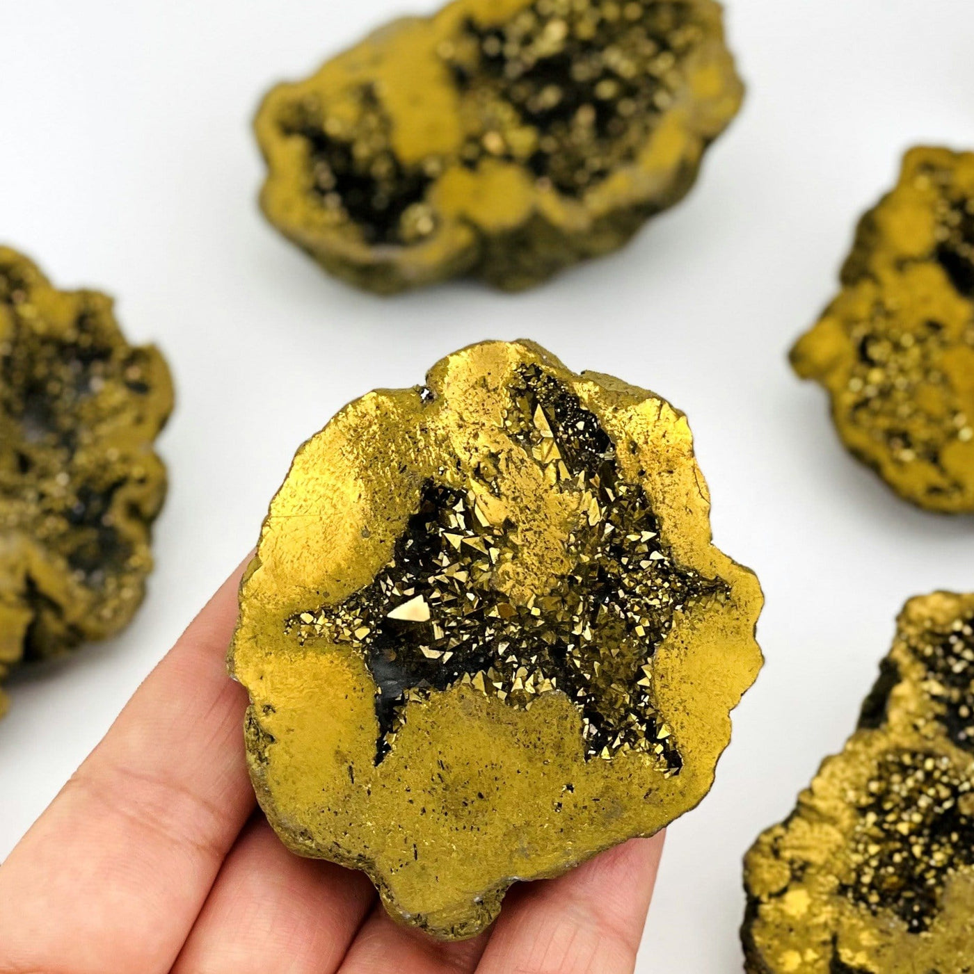 Gold Half Geode close up in hand with a few in background for size reference