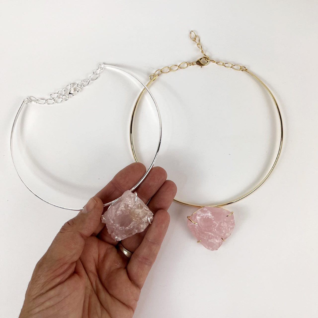 Rose quartz choker in gold and silver in a hand for sizing