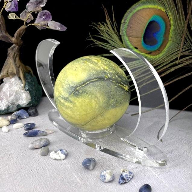A close up of Acrylic Sphere Holder Crescent Moons - Clear Base holding a sphere surrounded with crystals.