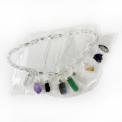 silver gemstone and crystal charm necklace on a table
