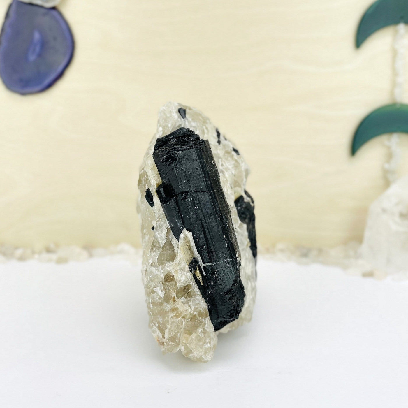 side view of Black Tourmaline on Matrix with decorations in the background