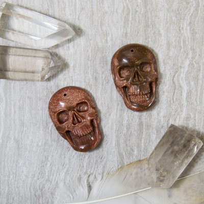 overhead view of two skull shaped goldstone pieces on display for possible variations and details