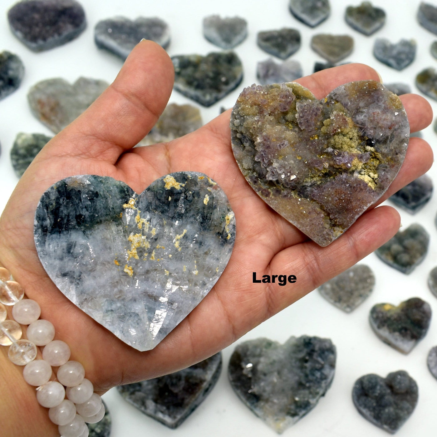 hand holding up 2 large Amethyst Flower Hearts