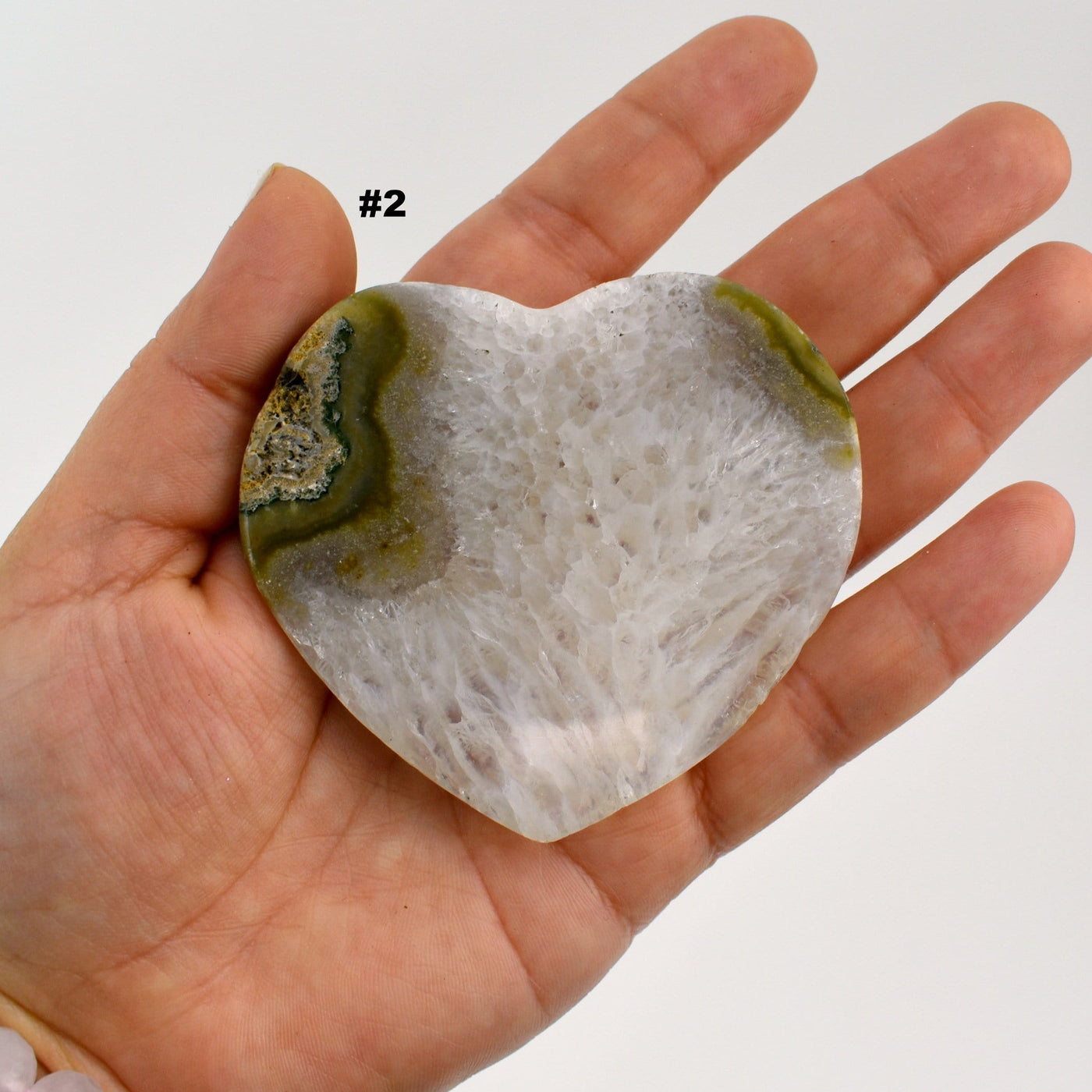 Agate heart slice #2 in a hand with a white background.