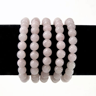 rose quartz healing stone bracelets on a display stand with white background