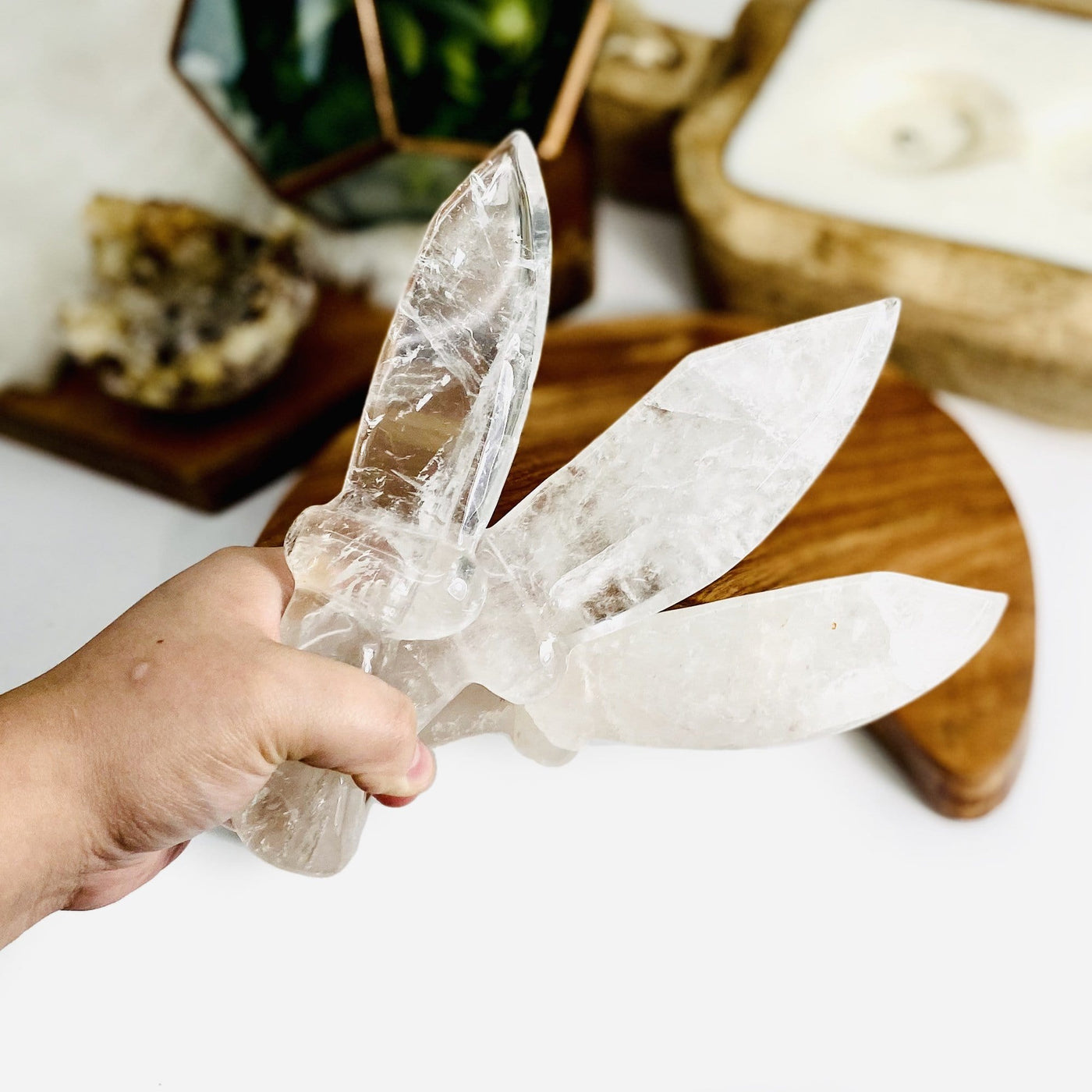hand holding up 3 Crystal Quartz Knifes with decorations in the background