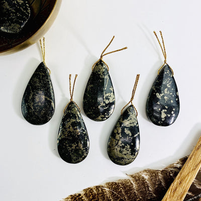 5 pyrite tumbled pendants on white background with decorations