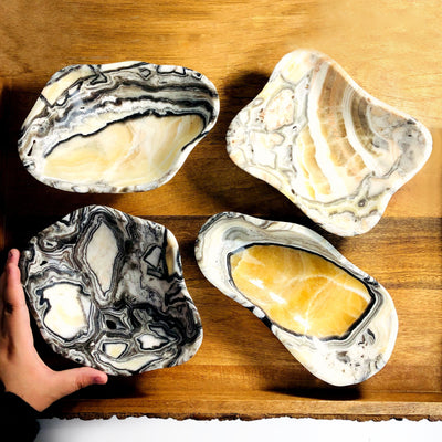 4 Mexican Onyx Freeform Bowls displayed to show various characteristics with a hand on the side for size reference