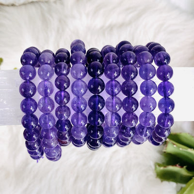 9 amethyst round beaded bracelets displaced on a piece of selenite.