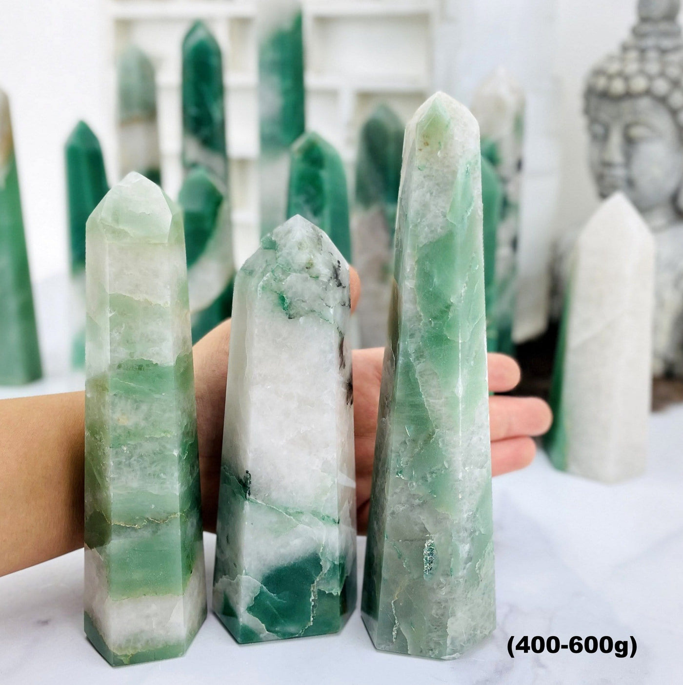 Green and White Quartz Polished Points--front shot view of 400 to 600 grams with different tones and sizes with hand comparison.