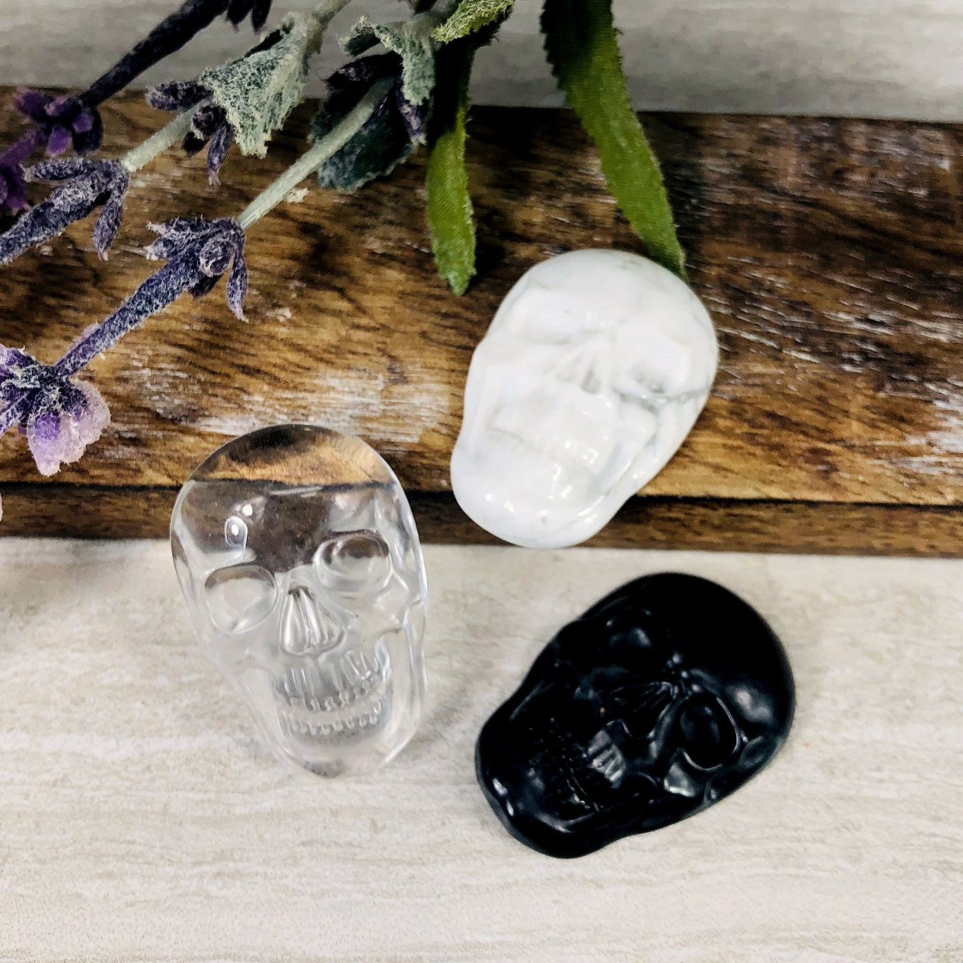 3 crystal skull cabochons on wooden plank with decorations