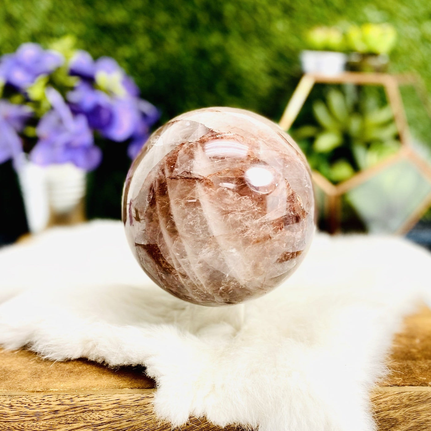 Hematoid Quartz Polished Sphere with decorations in the background