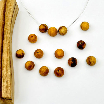 drilled palo santo beads displayed on a wire necklace. chain not included 