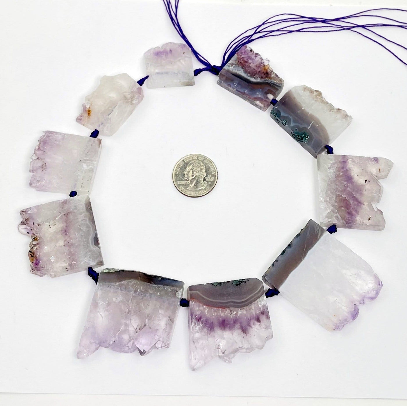 string of amethyst slice beads circled around a quarter for size reference on white background