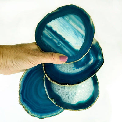 Hand holding 4 piece set of teal agate electroplated edge in Gold 