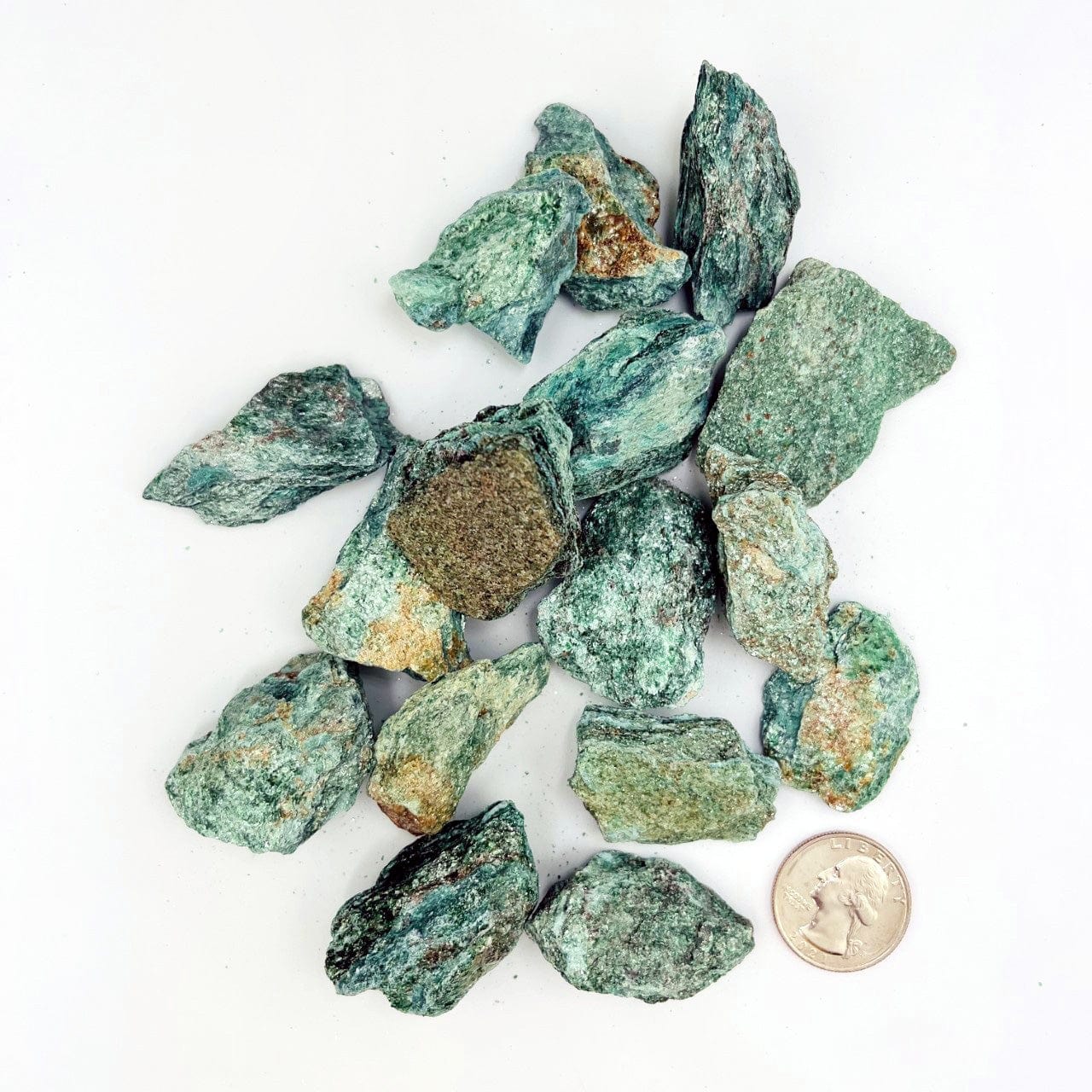 a bunch of Fuchsite Natural Stones next to a quarter for size reference