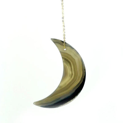 A drilled agate moon with a chain with a white background.