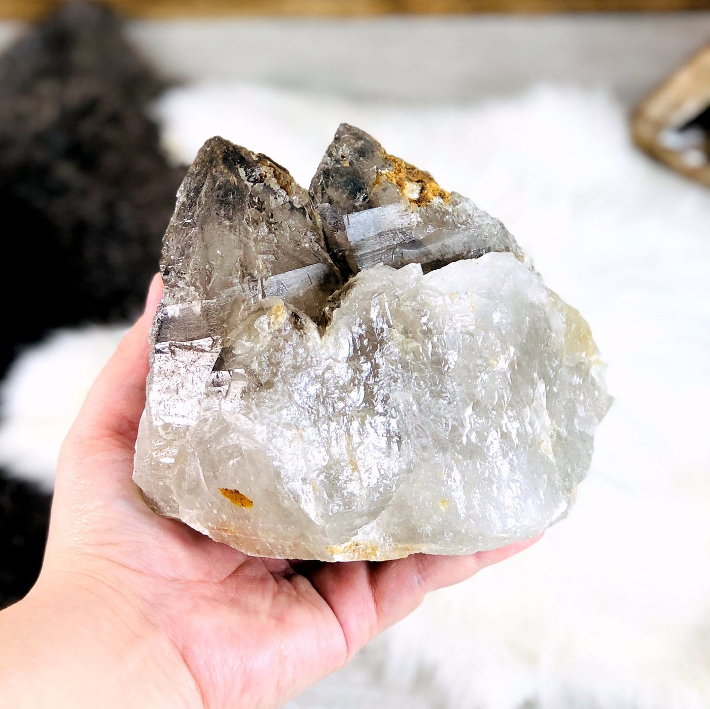 hand holding up Smokey Quartz raw Point with decorations in the background