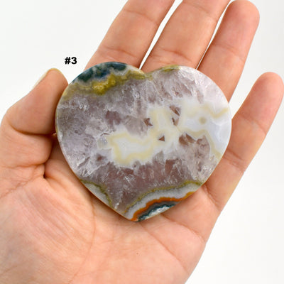Agate heart slice #3 in a hand with a white background.