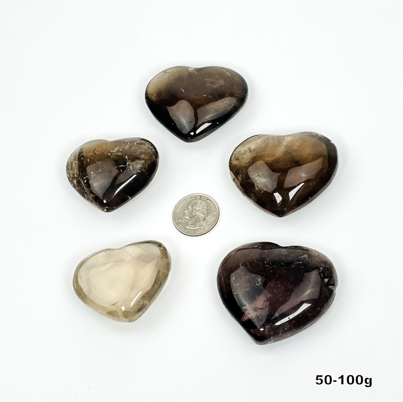 five 50g - 100g smokey quartz polished hearts on white background for possible variations  with quarter for size reference