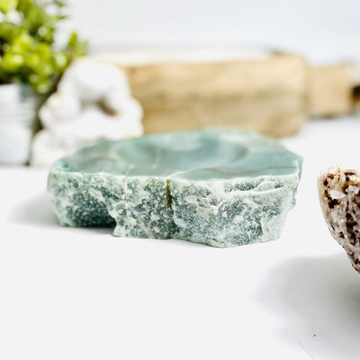 side view of Green Aventurine Semi-Polished Bowl with decorations blurred in the background
