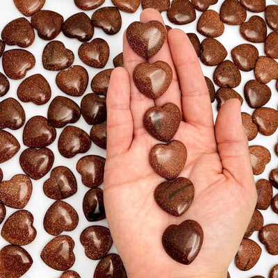 multiple heart shaped goldstone on a hand for reference size