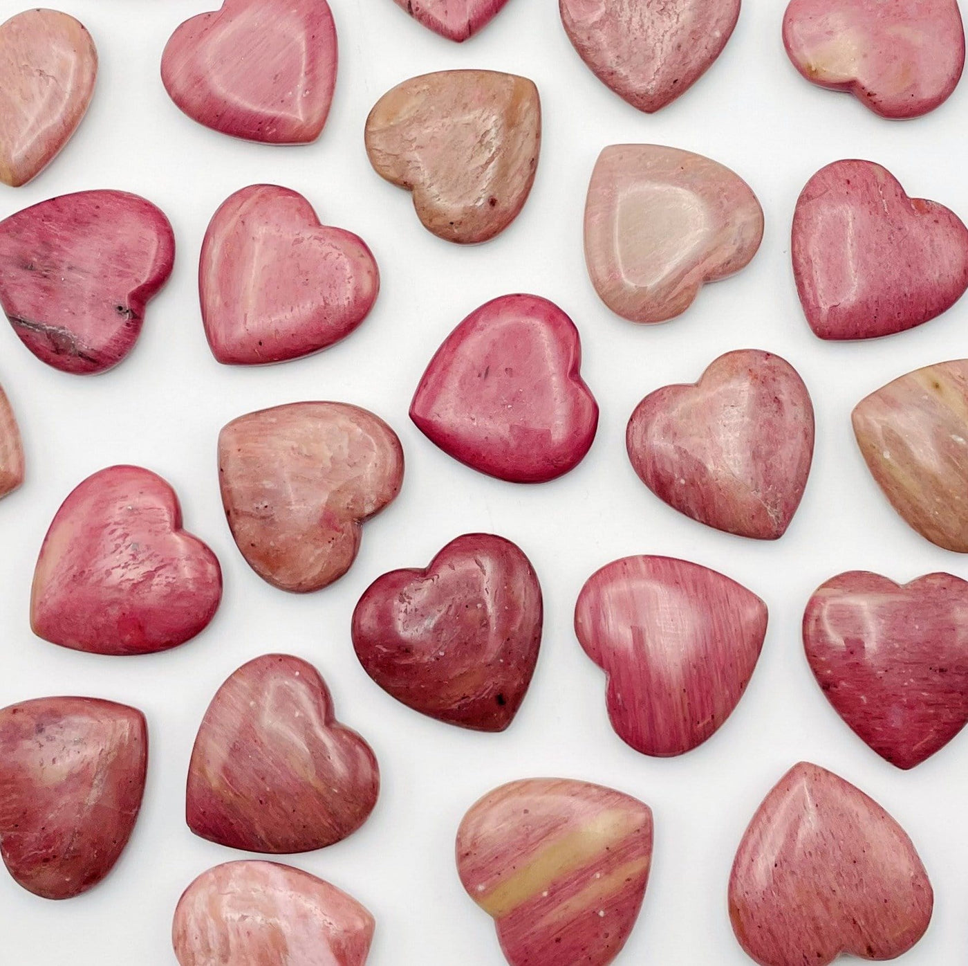 Rhodonite Heart Shaped Stones scattered on white background