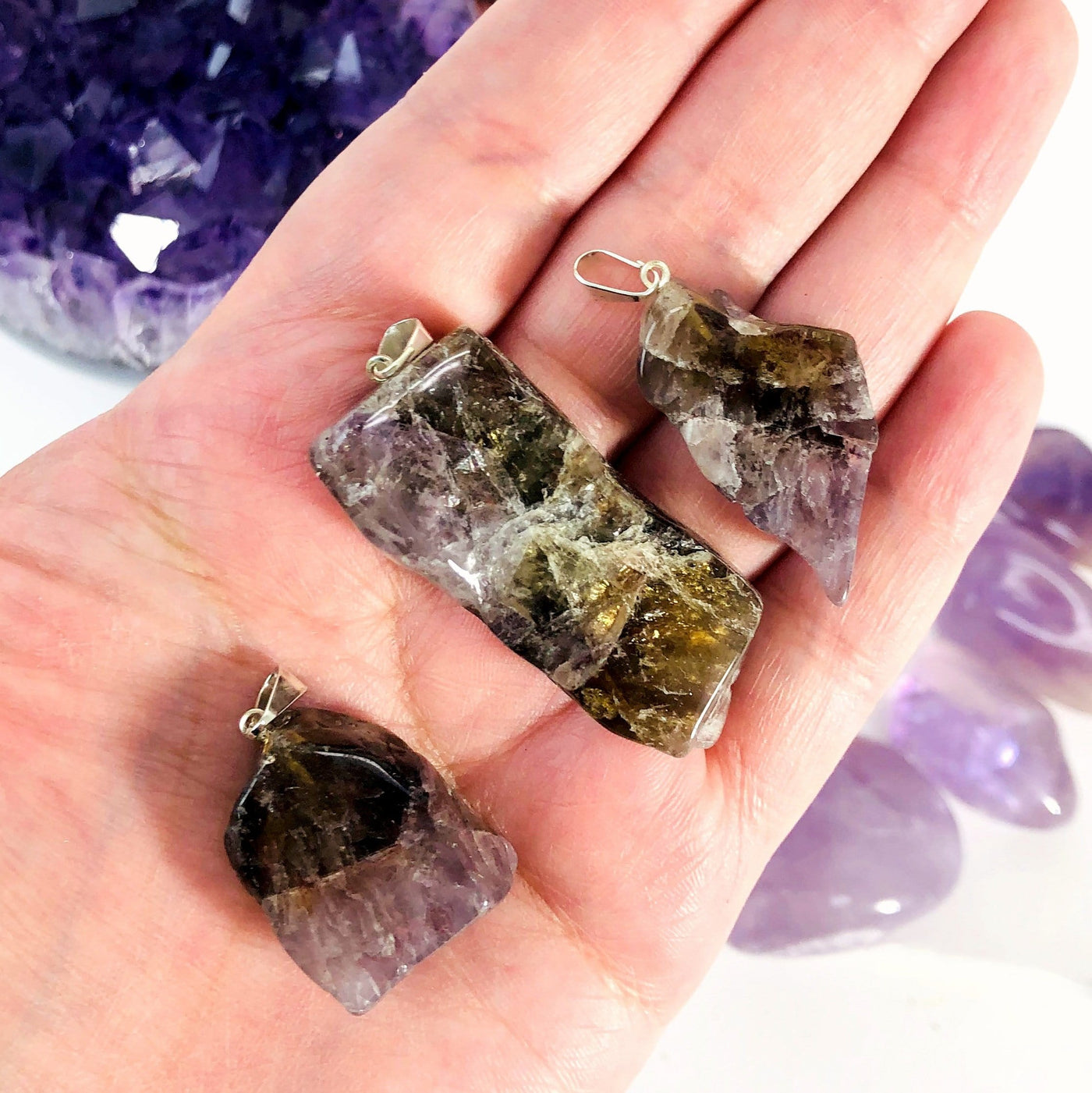 three seven minerals in one stone free form slab pendants in hand for size reference