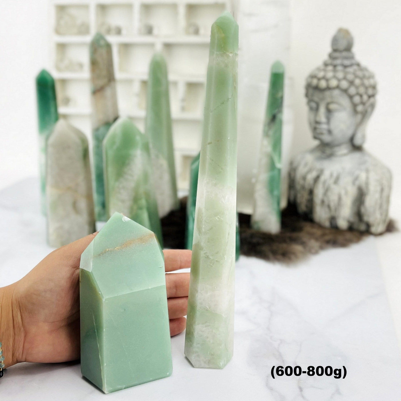 Green and White Quartz Polished Points--front shot view with different tones and sizes with hand comparison.
