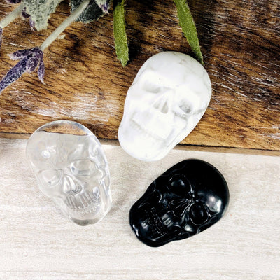3 different crystal skull cabochons on wood plank with decorations
