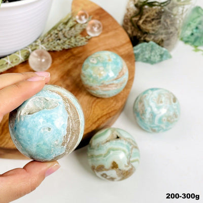 Blue Aragonite Spheres - Also known as Caribbean Calcite, shown with one in a hand and others in the background