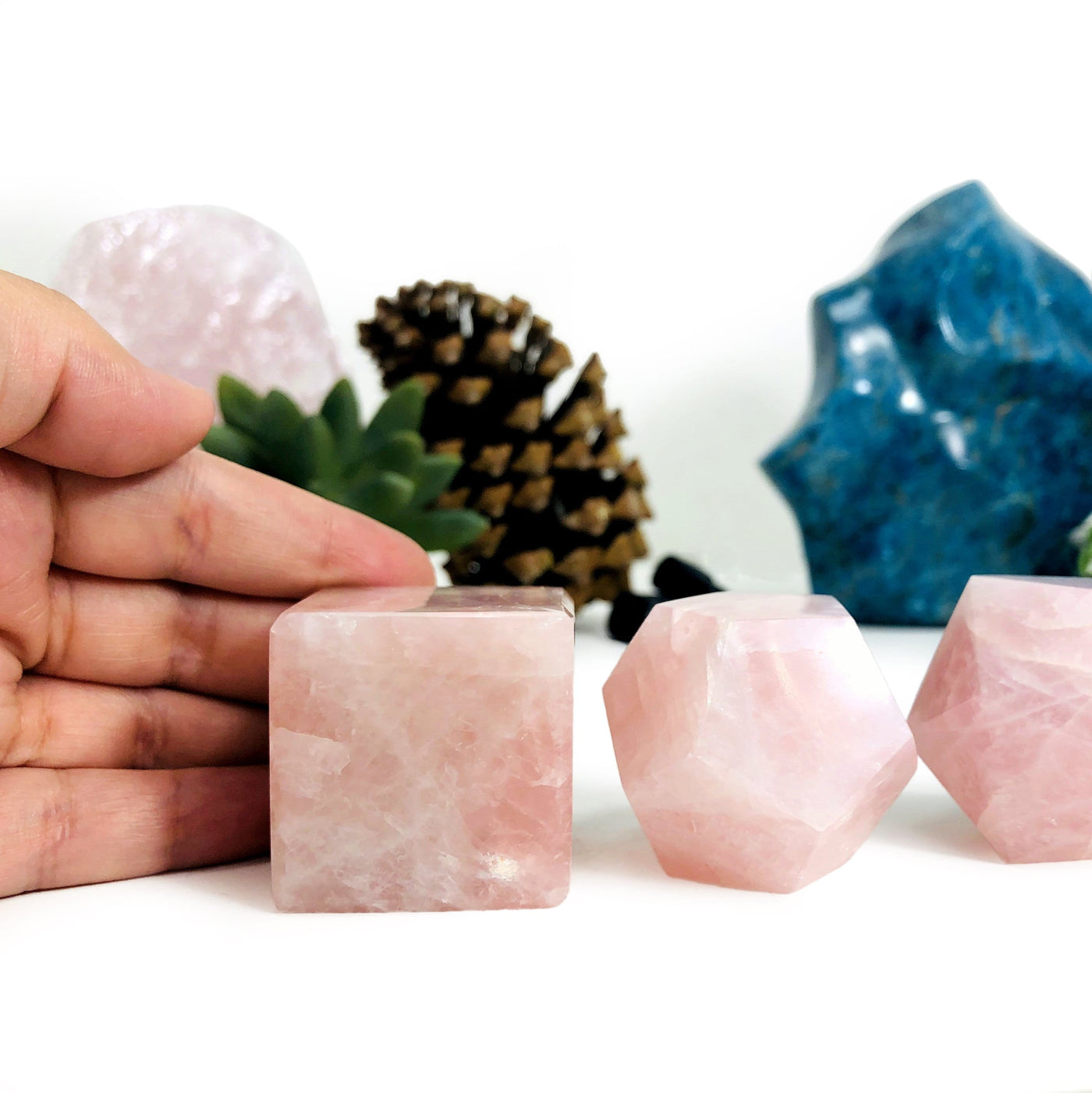 Hand touching Rose Quartz Sacred Geometry Meditation Set with decorations blurred in the background