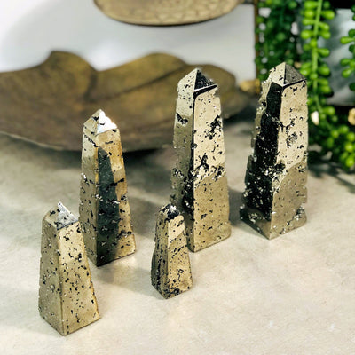 Shows five different sizes of pyrite obelisk towers on a table top.