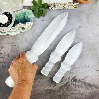 3 sizes of Selenite Knives with Twisted Handles, one with a hand for size reference