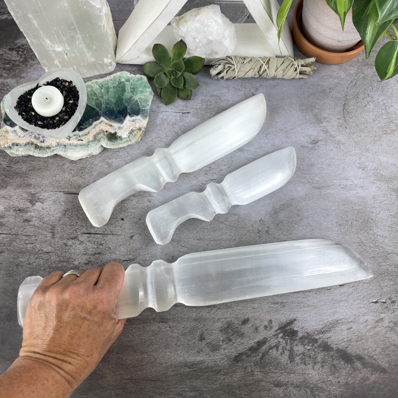 3 sizes of Selenite Knives with Hand Cut and Polished Handles with the large one in a hand for size