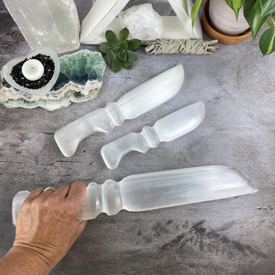 3 sizes of Selenite Knives with Hand Cut and Polished Handles with the large one in a hand for size